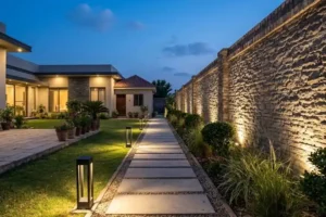 Architectural lighting for modern garden paths and walls at dusk with warm bollard lights and a softly lit stone wall